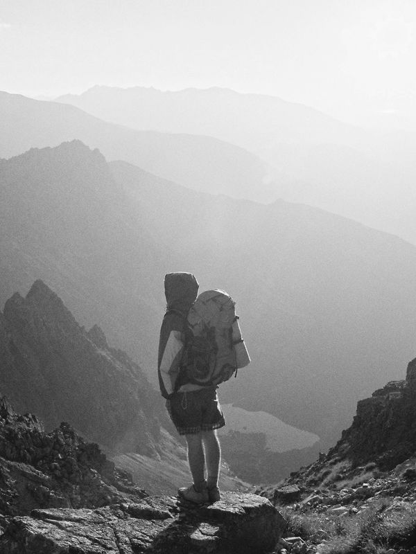 Woman explorer with backpack looking over mountain range