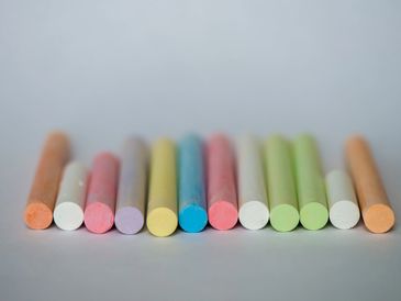 Colorful chalk sticks arranged in a row on a gray surface.