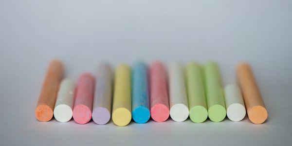 Colorful chalk sticks arranged in a row on a gray surface.