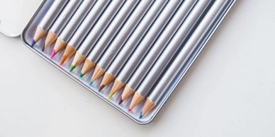 Set of colored pencils neatly arranged in a metal case.