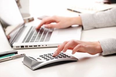 hands typing on laptop and calculator 