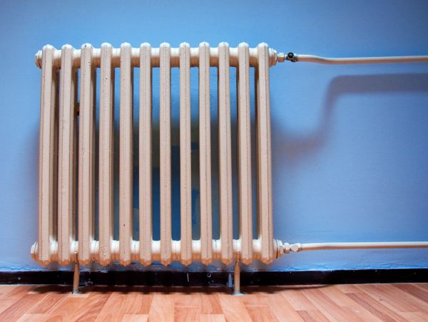 Old white radiator against a blue wall.