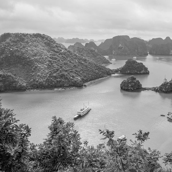 Scenic bay with emerald waters, limestone islands, and boats.