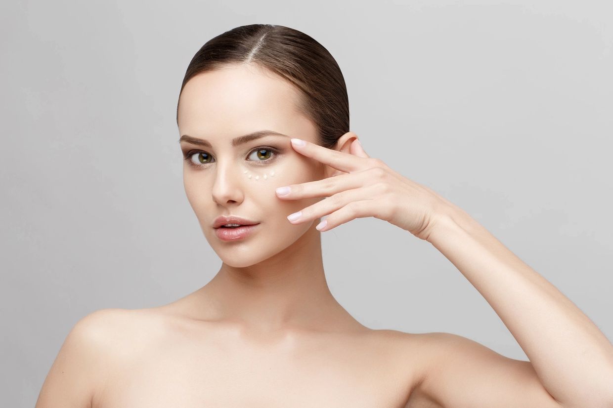 Woman applying eye cream under her eyes.