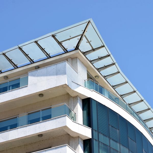 Modern building corner with glass and concrete under clear sky.