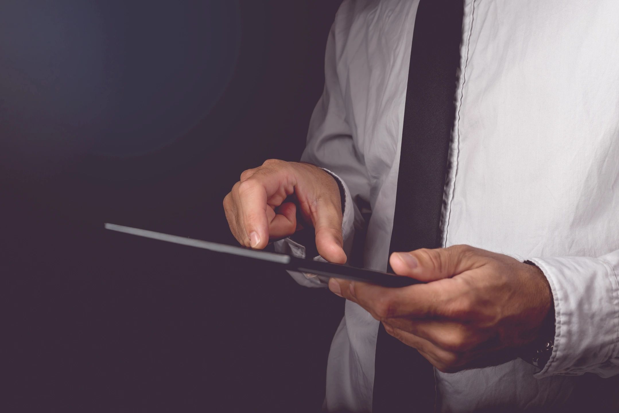 Employee wearing a black tie using a tablet for work.