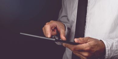 I man in a shirt and tie who is reviewing information on his tablet.