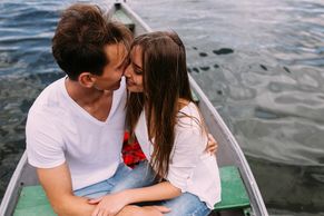 A young man and woman, sitting in a rowing boat, kissing.