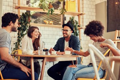 group of people, sitting at a table, drinking coffee, laughing and smiling 