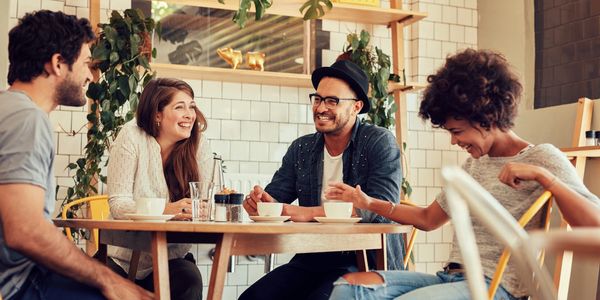 Four friends enjoying laughter and conversation around a cafe table.