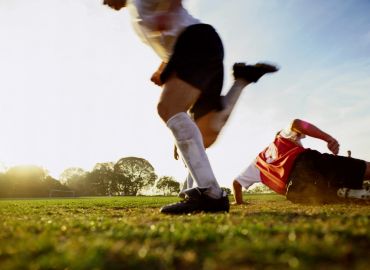 Soccer players competing on the field during sunset.