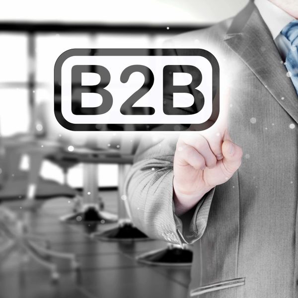 Businessman in suit pointing at B2B icon in office setting.