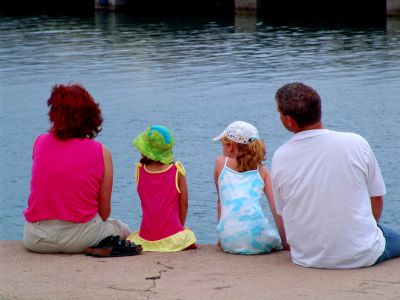 A family of four sitting by the water, enjoying a peaceful moment.