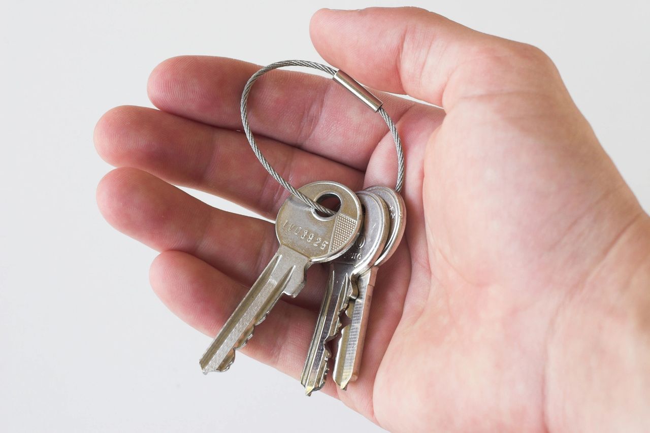 A open hand holds three keys on a key ring.