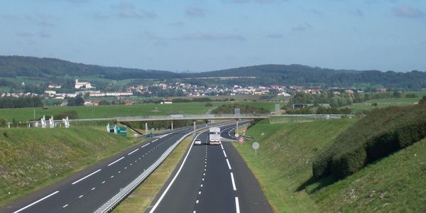 A highway with a bridge overpass in a rural landscape under a partly cloudy sky.