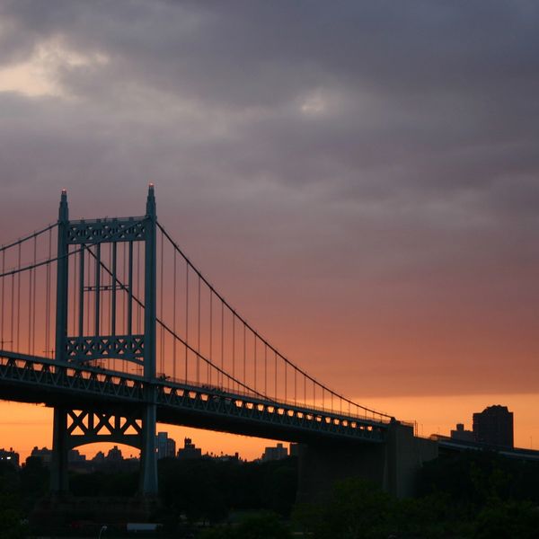 Suspension bridge silhouetted against a vibrant sunset sky.