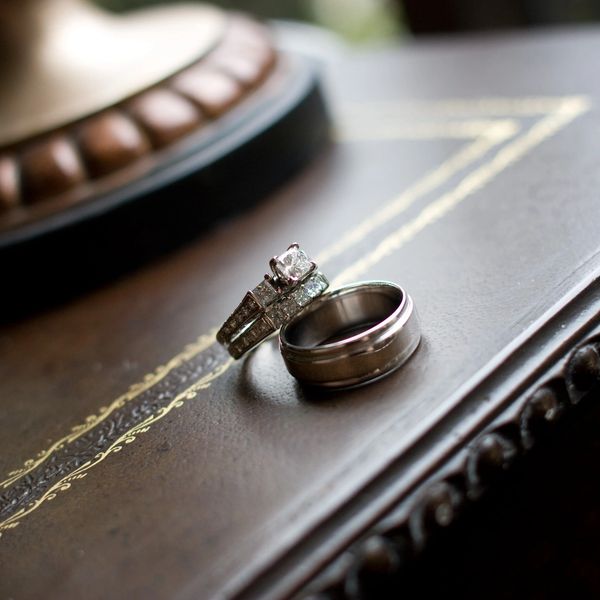A pair of wedding rings on a dark, ornate surface.