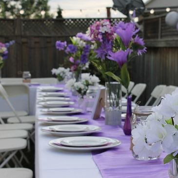 Elegantly set dining table with floral centerpiece and lit candles.