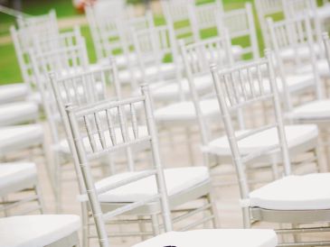 Des chaises blanches alignées en extérieur.