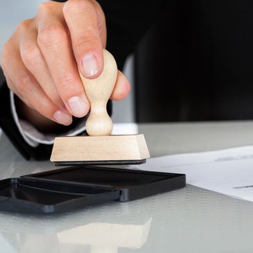 Notary placing notary stamp in ink to stamp a document.