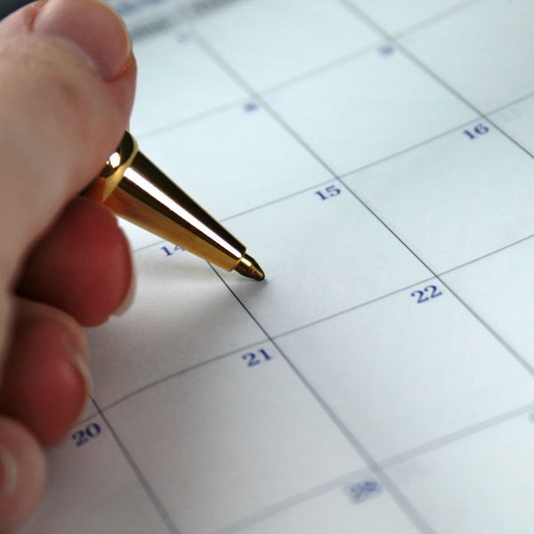desk calendar with a hand holding a pen