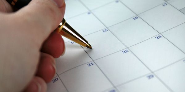 Pen in hand writing notes on a calendar
