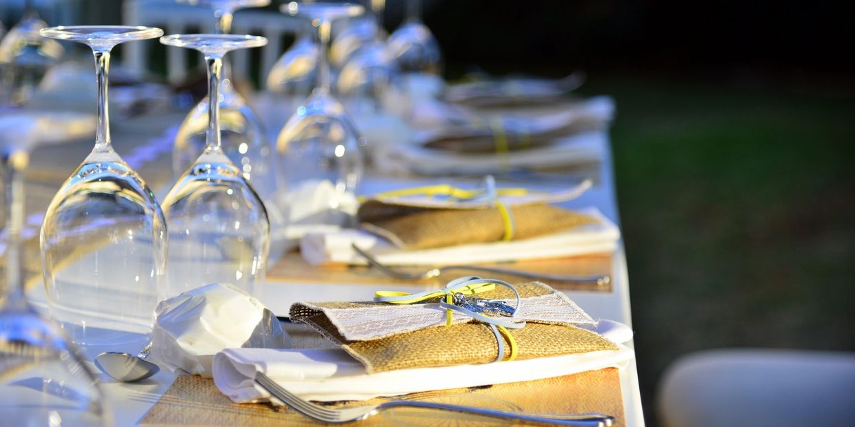 Elegant outdoor dining table set with wine glasses and napkins.