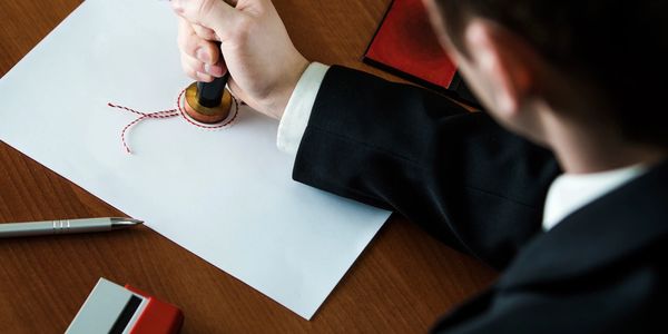 A man with a Notary stamp, ink pad, writing pen and a self-inking notary stamp notarizing a document