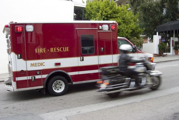 A fire rescue medic vehicle with a motorcycle passing by quickly.