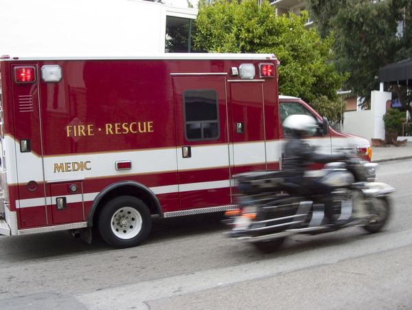 Ambulance driving next to a police officer on a motorcylce