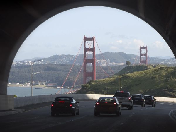 Cars driving towards the Golden Gate Bridge through a tunnel.