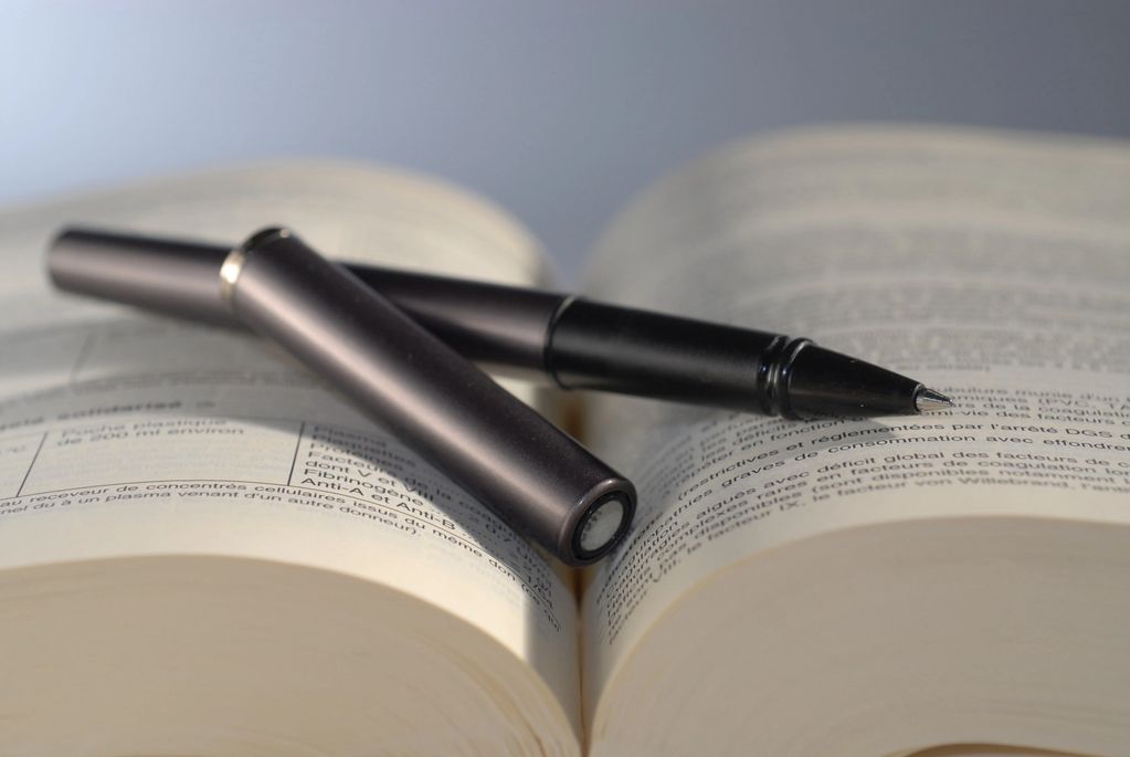 A black pen lying open on a book with text visible.