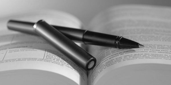 A black pen resting on an open book with text in focus.