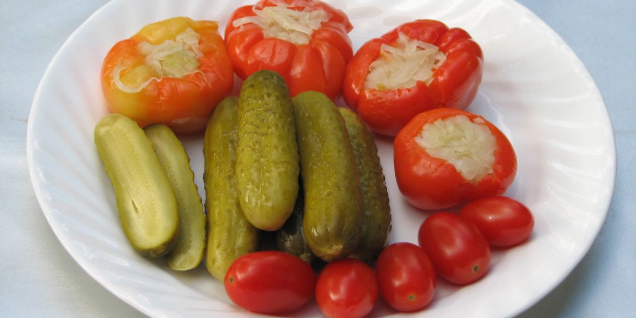 Plate of stuffed peppers, pickles, and cherry tomatoes.