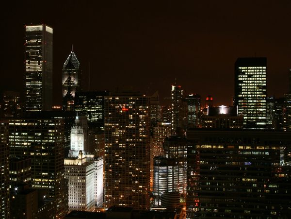 Night view of a city skyline with illuminated skyscrapers.
