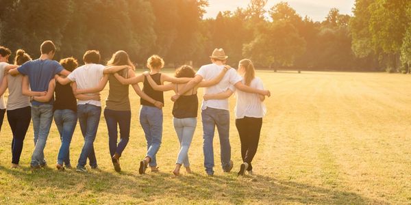 Group of friends linking arms walking in a park