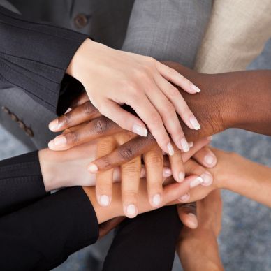 Diverse hands stacked together symbolizing unity and teamwork.