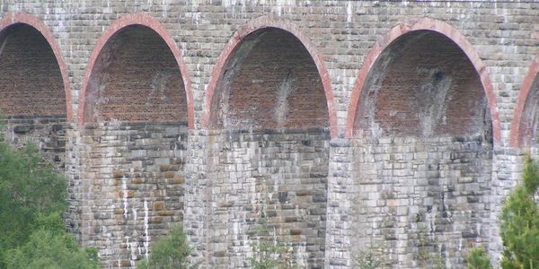 Close-up of a stone arch bridge with red brick arches.
