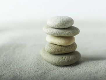 A stack of smooth stones balanced on sand.