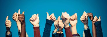 Diverse group of hands showing thumbs up against a blue background.