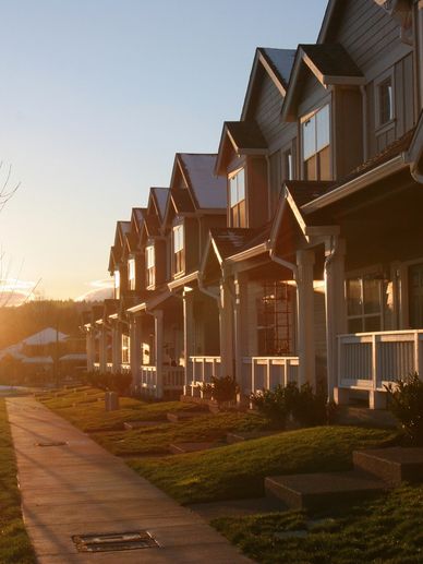 Sunset casts warm light on a row of modern suburban houses.