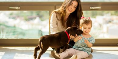 Mother with daughter and puppy indoors.