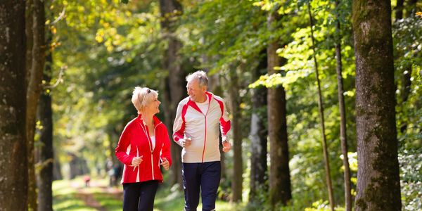 Two middle-aged people jogging in a park. 