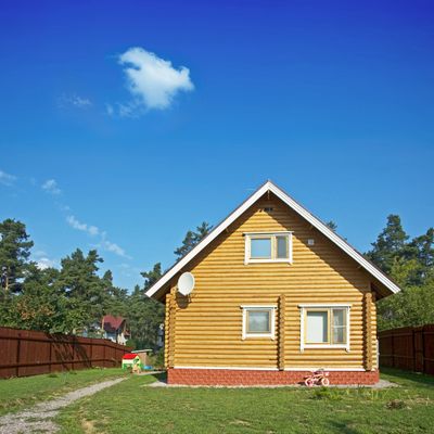 Wooden house with a triangular roof under a clear blue sky.