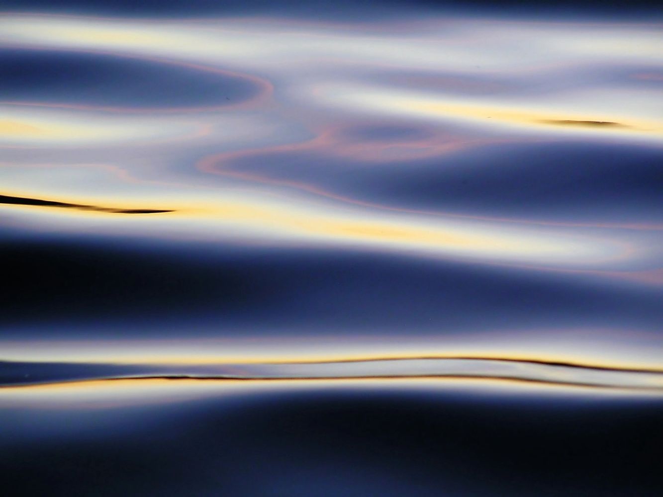 Smooth water surface reflecting soft twilight colors.