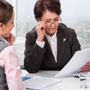 Generic photo of lawyer and client reviewing documents at desk.