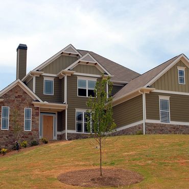 Modern two-story house with stone and siding exterior on a grassy hill.