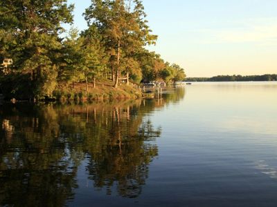 Calm lake with trees reflecting on the water at sunset.