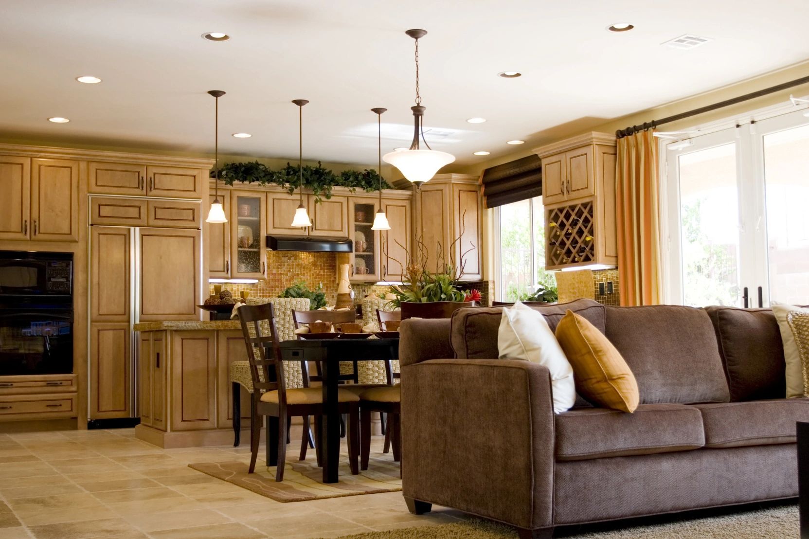 Cozy open-plan kitchen and living room with warm wooden cabinetry and plush brown sofa.