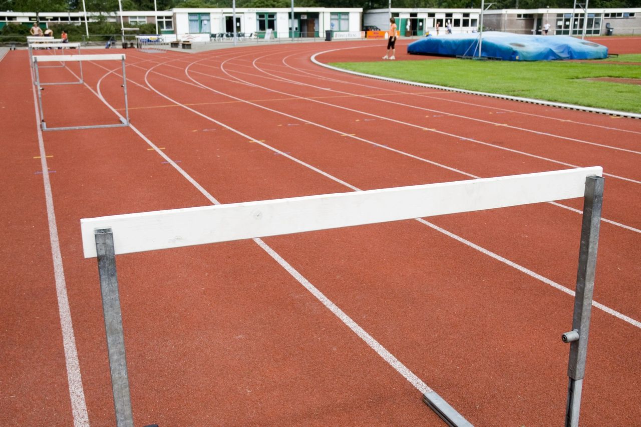 Hurdles along a track field as the runners line-up.